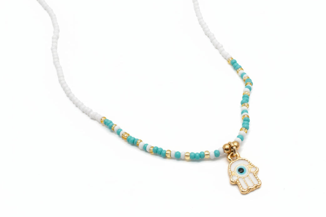 Necklace with blue and gold beads and a Hamsa hand charm on a white background